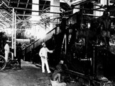 Het interieur van het molenhuis met de Fletchermolen op de suikeronderneming Kalibagor, Java, 1905. Op de voorgrond de tweede machinist Van Stenus, op de achtergrond de eerste machinist Ottenhoff.<br />
(Foto collectie Tropenmuseum, Amsterdam, coll.nr 60004334)<br />
